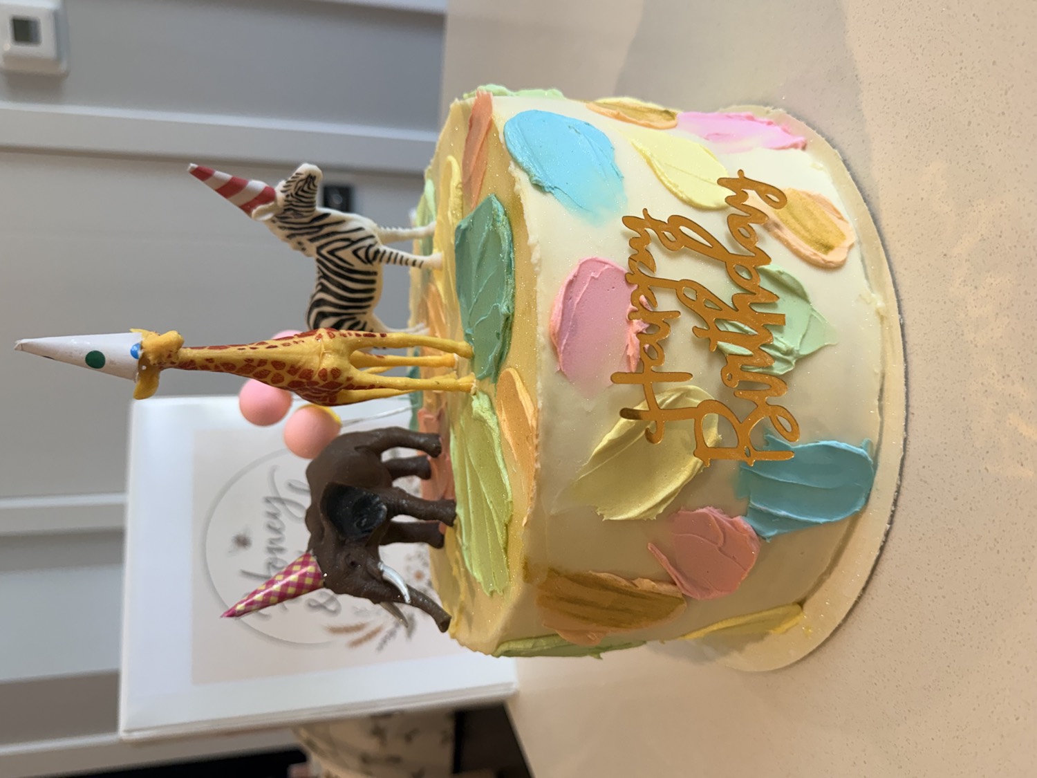 Pastel buttercream birthday cake with safari animal toppers