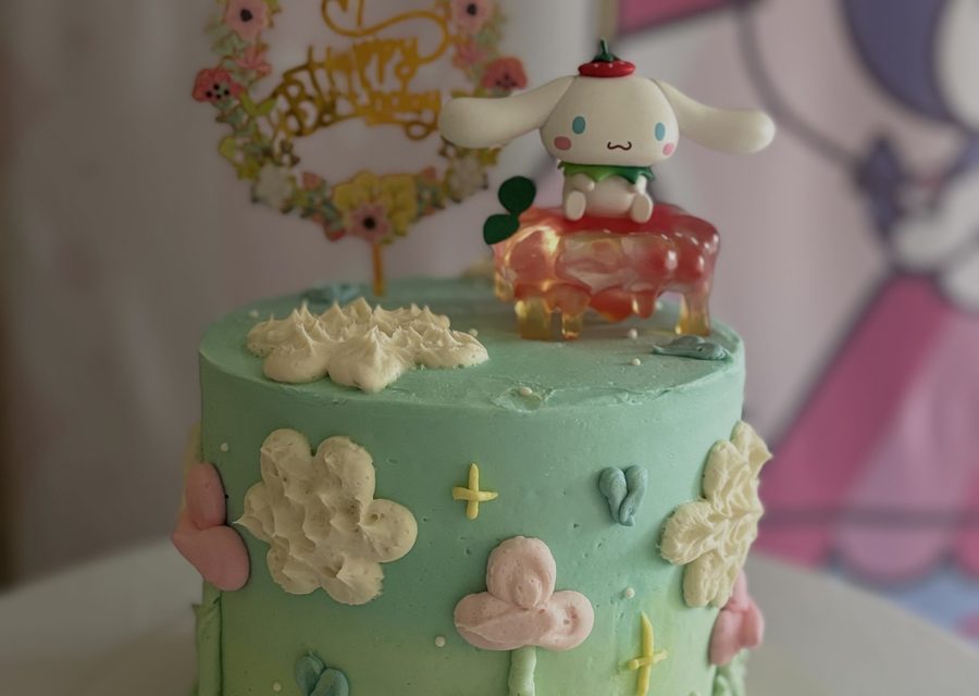 Pastel green cake decorated with piped clouds and character toppers