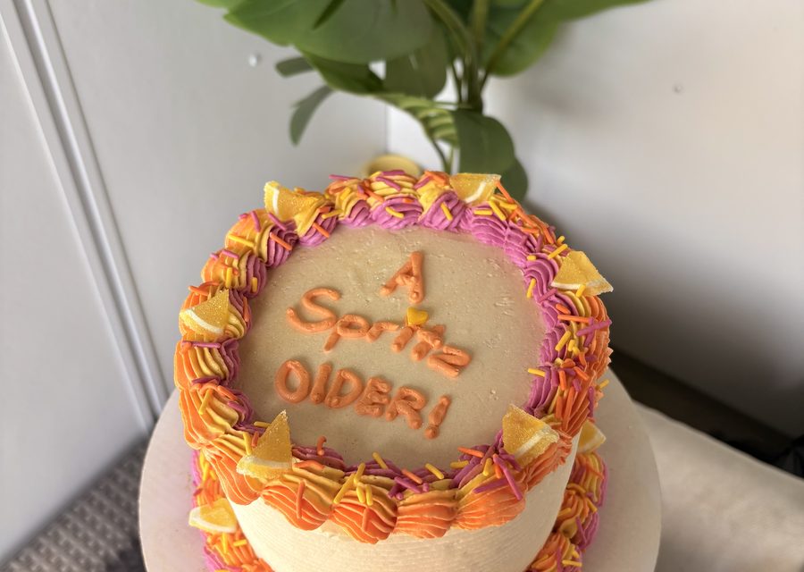 Bright pink and orange birthday cake with piped lettering