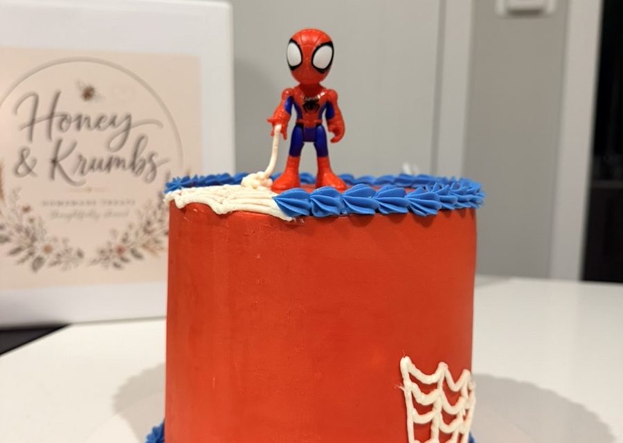Red and blue superhero birthday cake with a figurine on top
